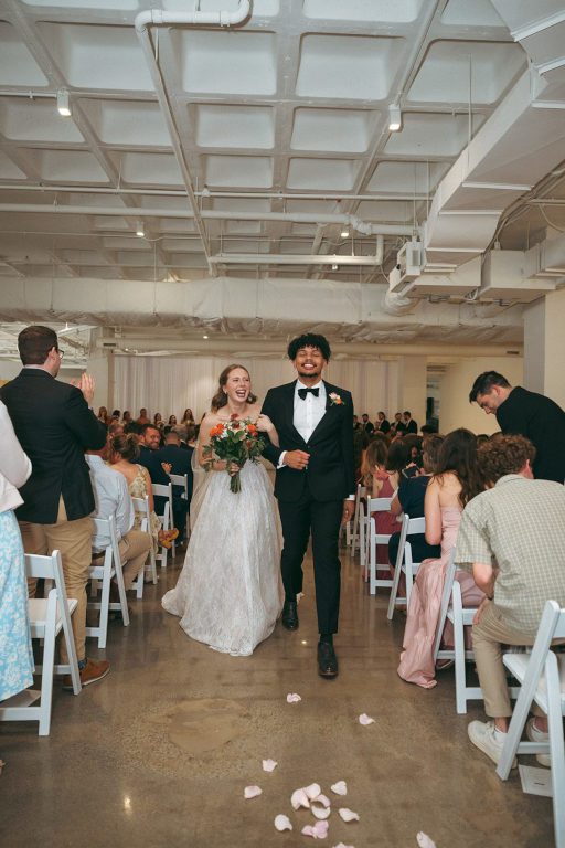 weddings-body-banner-01 ust-married couple walking hand-in-hand down the aisle at lightwell Gallery, a modern Kansas City wedding venue.