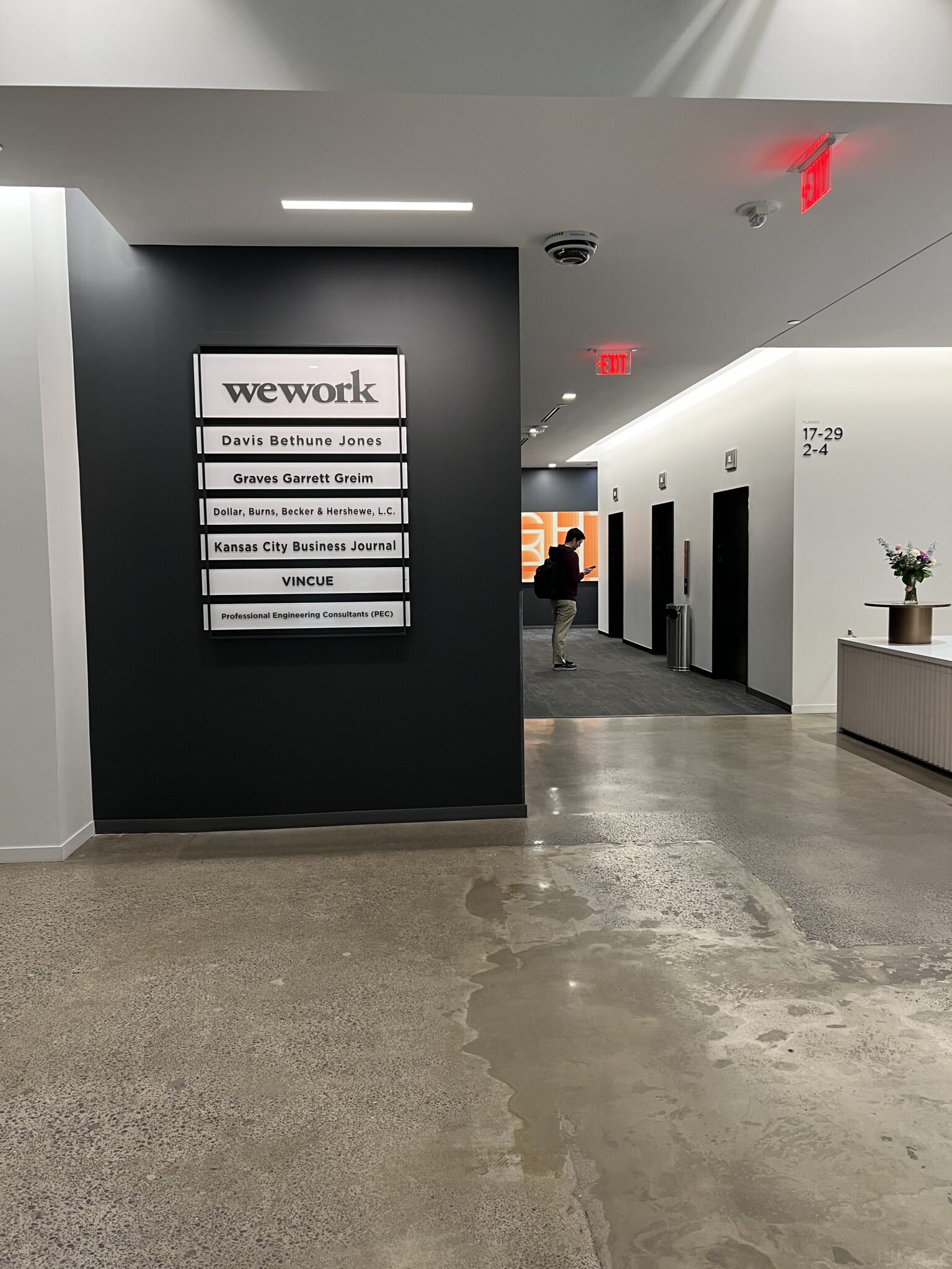 The lobby of Lightwell KC featuring modern signage, a sleek front desk, and a bank of elevators with clean, minimalist design.
