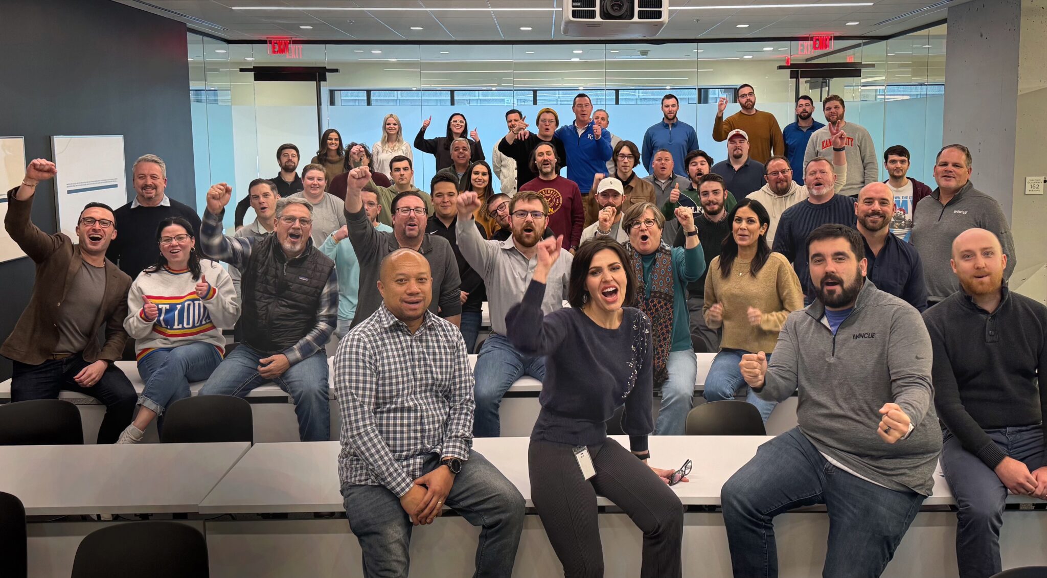 The Vincue team gathered in the Lightwell KC training room during a company outing, seated and standing in a modern conference space with bright lighting and collaborative energy.